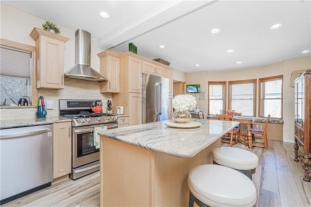 kitchen with wall chimney exhaust hood, stainless steel appliances, decorative backsplash, and light wood-style flooring