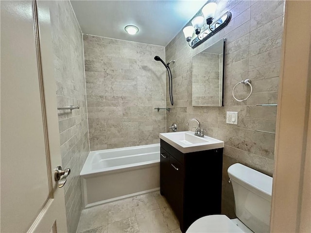 bathroom with tile walls, bathing tub / shower combination, toilet, and vanity