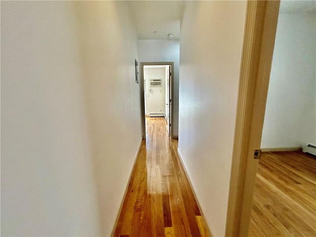 hallway with an AC wall unit, wood finished floors, and baseboards