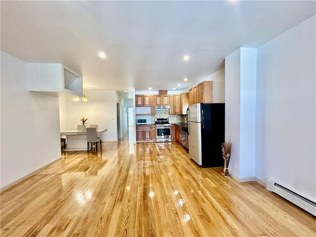 kitchen featuring baseboards, light wood-style floors, under cabinet range hood, appliances with stainless steel finishes, and a baseboard heating unit