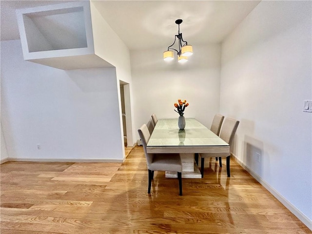 dining area with a chandelier, light wood-style flooring, and baseboards