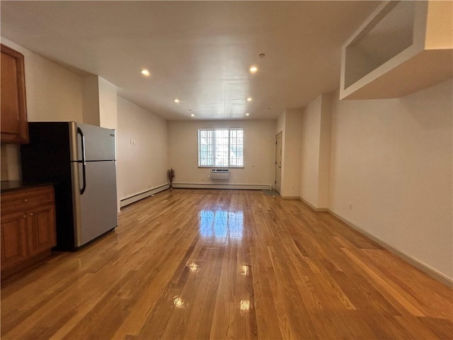 interior space with recessed lighting, a baseboard heating unit, baseboards, light wood-style floors, and a wall mounted air conditioner