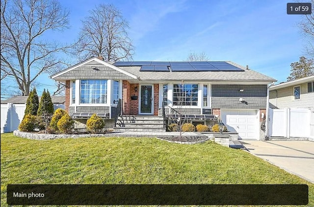 view of front of home with a front yard, fence, solar panels, and concrete driveway