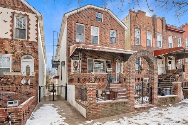 view of front of home featuring brick siding, a porch, and a gate