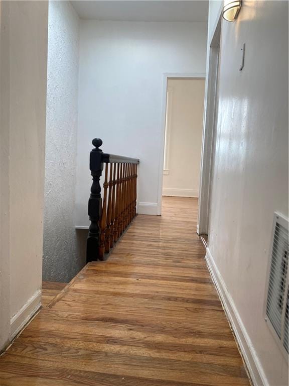 corridor with visible vents, wood finished floors, and a textured wall