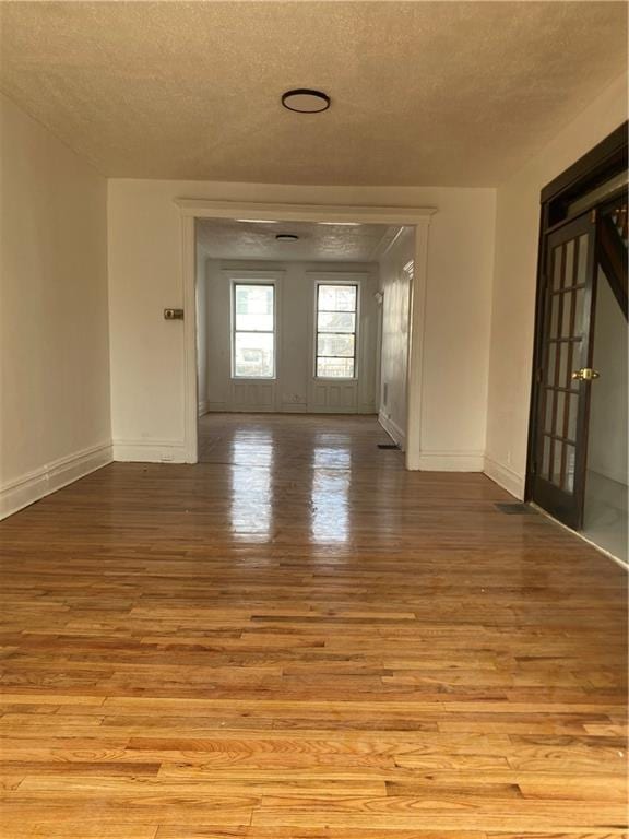 spare room with baseboards, a textured ceiling, and wood finished floors