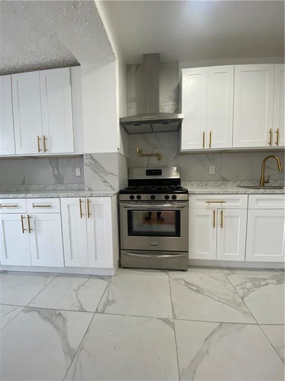 kitchen featuring wall chimney range hood, marble finish floor, stainless steel gas range, and a sink