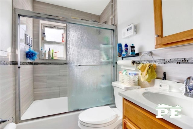 bathroom with toilet, enclosed tub / shower combo, decorative backsplash, and vanity