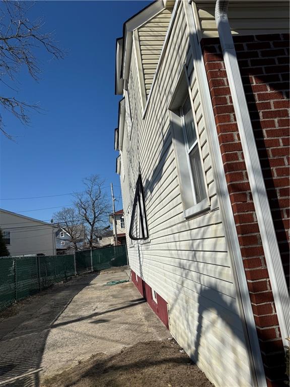 view of side of home with fence and brick siding