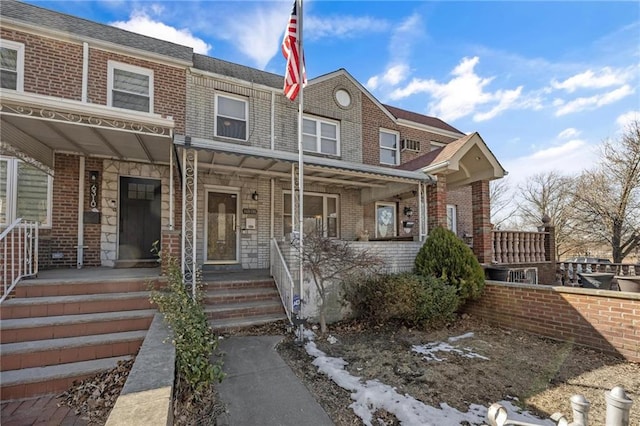 townhome / multi-family property featuring covered porch and brick siding