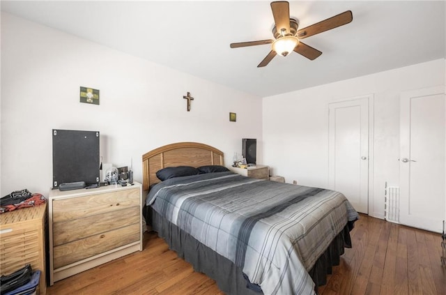 bedroom with ceiling fan, visible vents, and wood finished floors