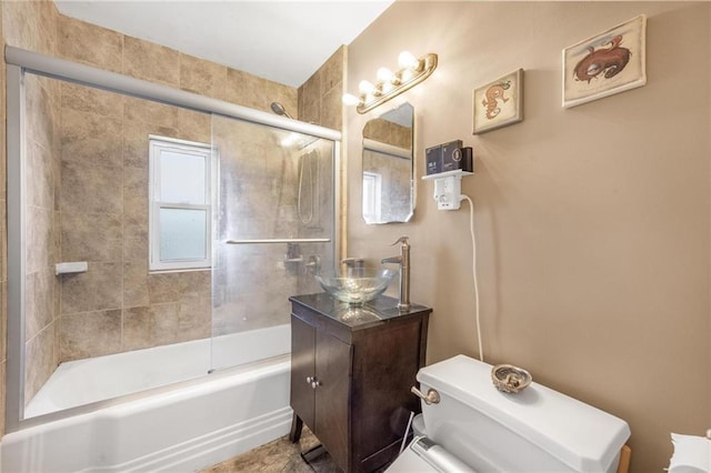 bathroom featuring combined bath / shower with glass door, a sink, and toilet