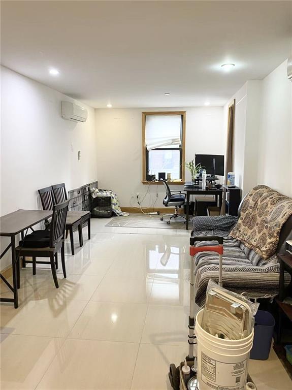 living area featuring light tile patterned floors, a wall mounted air conditioner, and recessed lighting