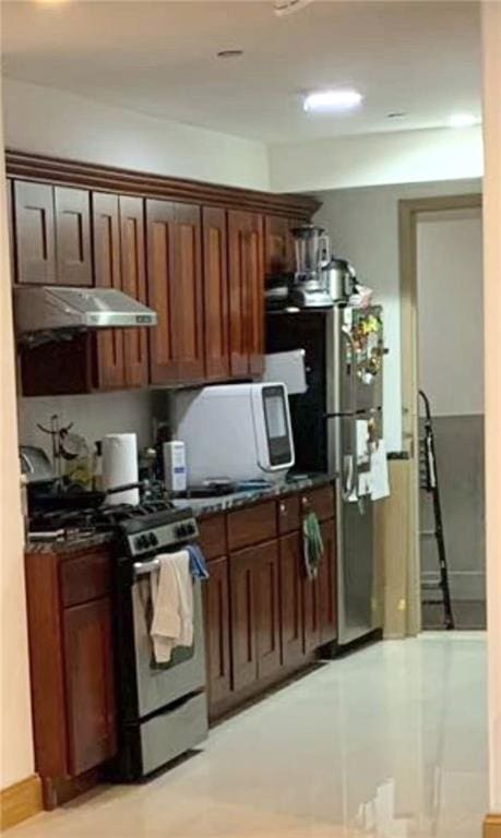 kitchen featuring gas stove, under cabinet range hood, freestanding refrigerator, and dark countertops