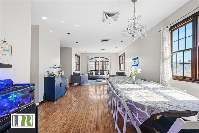 dining space featuring visible vents, a notable chandelier, and hardwood / wood-style floors