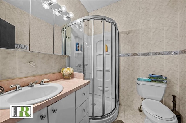 bathroom featuring toilet, a shower stall, tile walls, and vanity