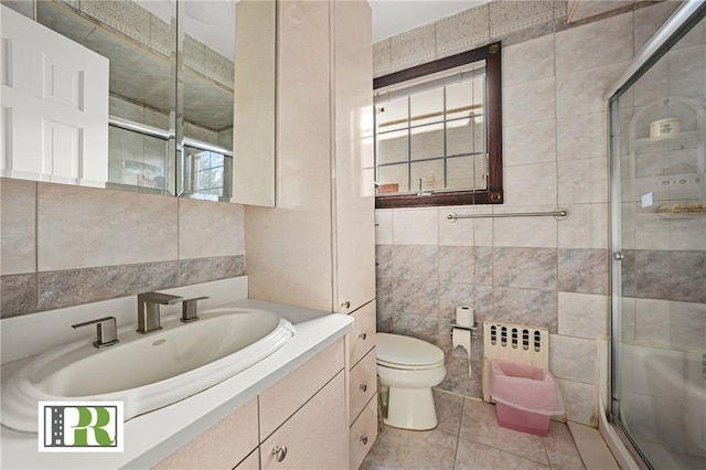full bath with a shower stall, tile patterned flooring, toilet, vanity, and tile walls