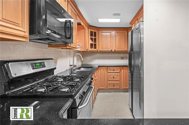 kitchen featuring stainless steel range with gas cooktop, glass insert cabinets, freestanding refrigerator, a sink, and black microwave