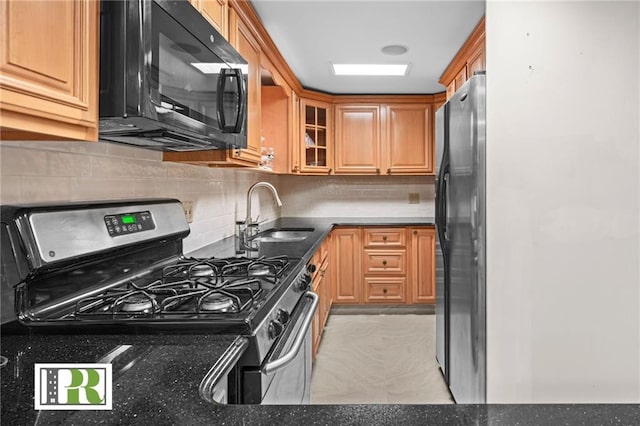 kitchen featuring backsplash, a sink, freestanding refrigerator, black microwave, and stainless steel gas range