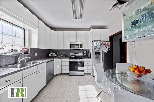 kitchen with a sink, visible vents, white cabinetry, appliances with stainless steel finishes, and backsplash