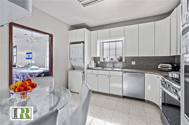 kitchen featuring tasteful backsplash, a chandelier, white cabinetry, appliances with stainless steel finishes, and stacked washer and dryer
