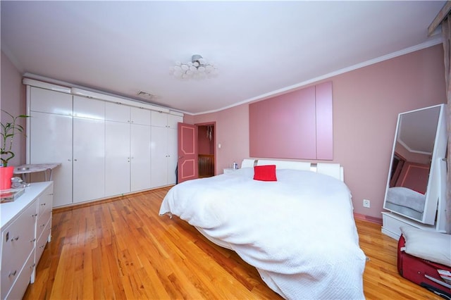 bedroom featuring light wood-type flooring, ornamental molding, and a closet
