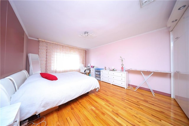 bedroom featuring light wood-type flooring, visible vents, ornamental molding, and baseboards