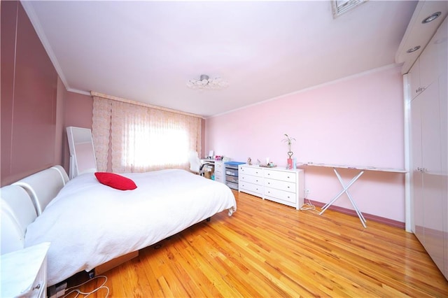 bedroom with ornamental molding, light wood finished floors, and baseboards