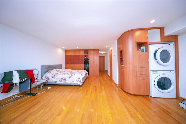 bedroom with light wood finished floors, stacked washer / dryer, and recessed lighting