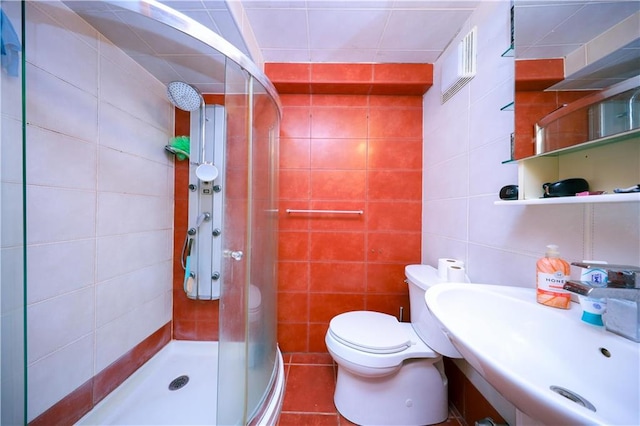 bathroom with toilet, a shower stall, a sink, and tile walls