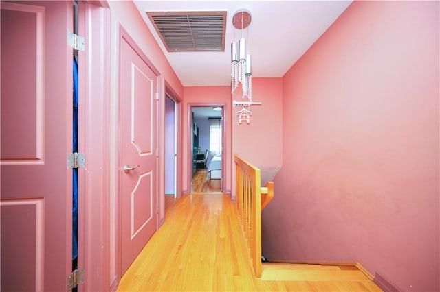 hall featuring light wood finished floors, baseboards, and visible vents