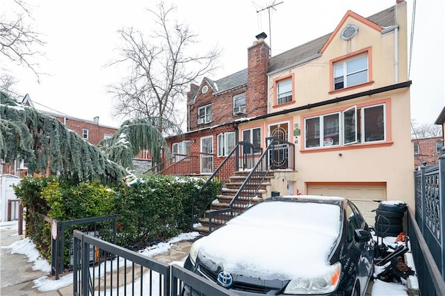 view of property featuring a garage, stucco siding, stairway, and a chimney