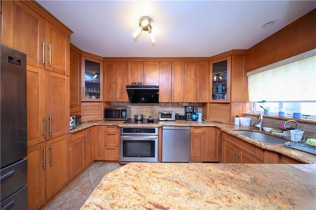 kitchen featuring stainless steel appliances, glass insert cabinets, and brown cabinets