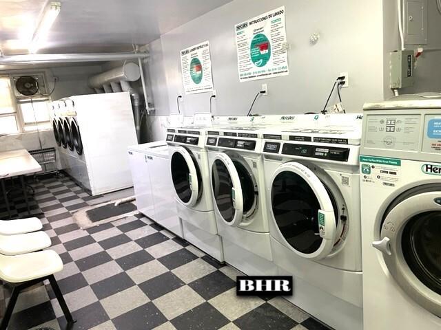 common laundry area featuring tile patterned floors, electric panel, and separate washer and dryer