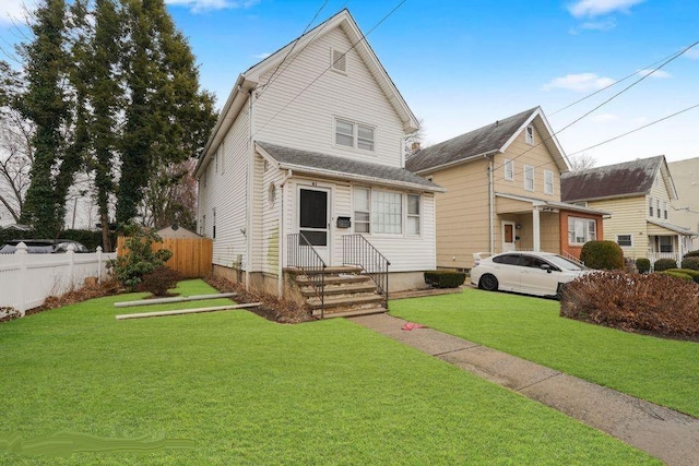 view of front of house with fence, entry steps, and a front yard