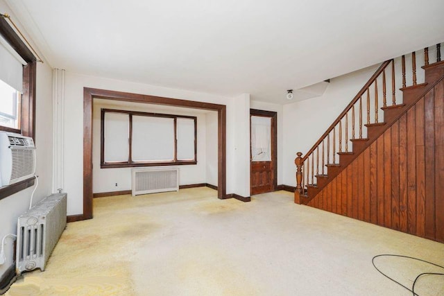 unfurnished living room with radiator heating unit, radiator, stairs, and carpet flooring