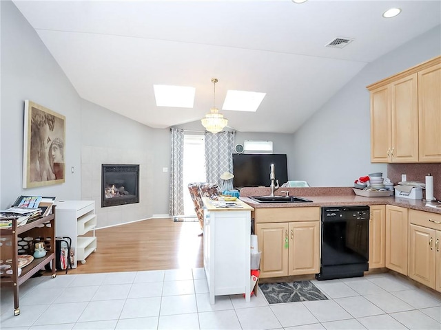 kitchen with vaulted ceiling with skylight, black dishwasher, visible vents, a peninsula, and light brown cabinets