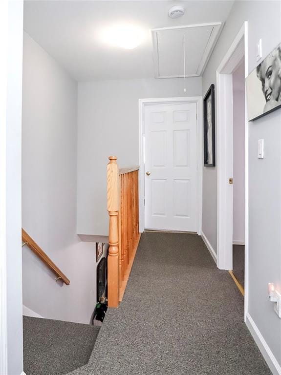 corridor with attic access, carpet floors, and baseboards