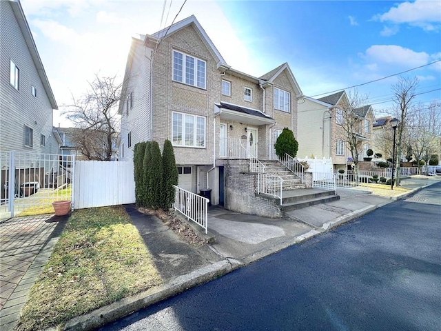 view of front of property with fence, an attached garage, a residential view, aphalt driveway, and brick siding