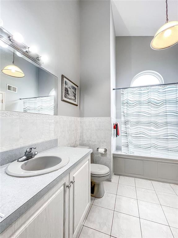 full bathroom with visible vents, toilet, tile patterned flooring, vanity, and tile walls