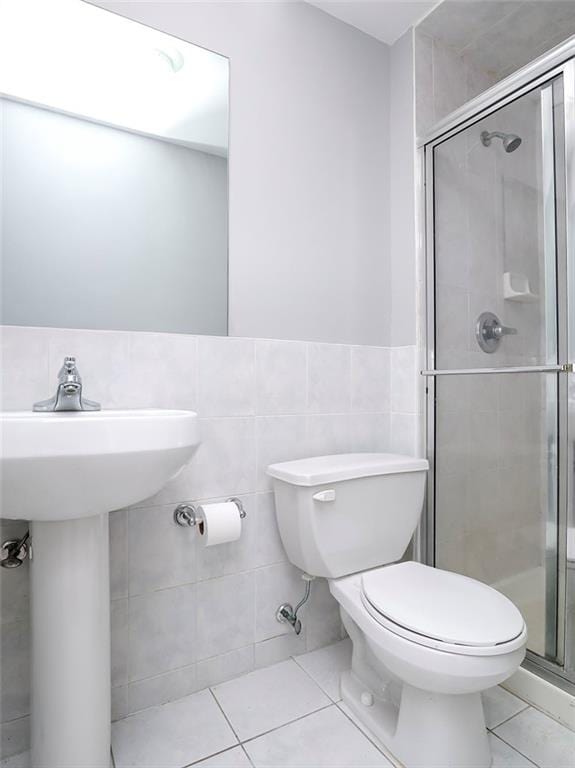 full bath featuring a stall shower, tile patterned flooring, tile walls, and toilet