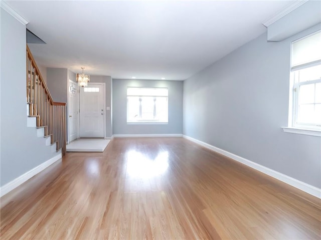 entryway with a wealth of natural light, baseboards, a chandelier, and light wood finished floors