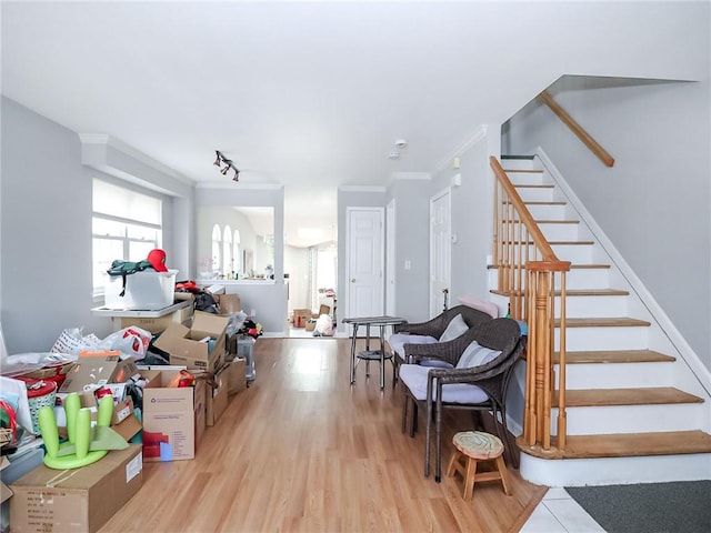 interior space featuring ornamental molding, wood finished floors, rail lighting, and baseboards