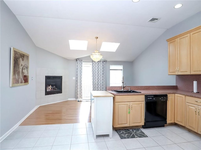 kitchen with light brown cabinets, a peninsula, a sink, black dishwasher, and lofted ceiling with skylight