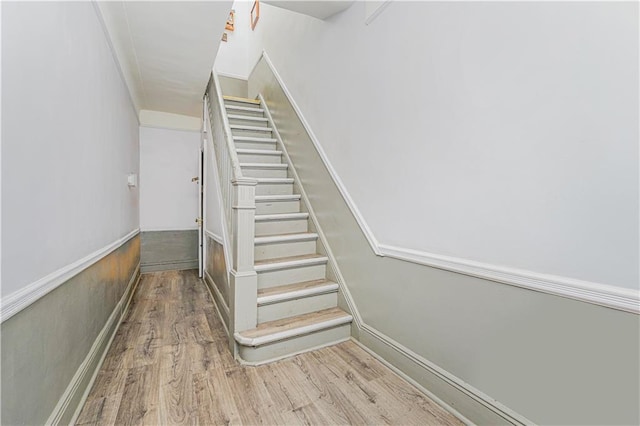 stairway featuring wainscoting and wood finished floors