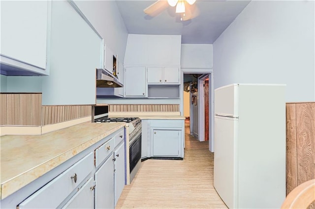 kitchen featuring light wood-style floors, freestanding refrigerator, light countertops, under cabinet range hood, and gas stove