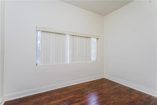 empty room with dark wood finished floors and baseboards