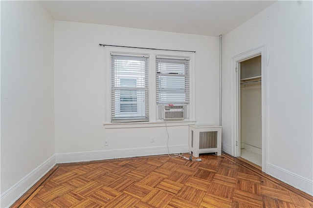 unfurnished bedroom featuring radiator, baseboards, and cooling unit