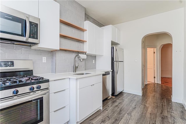 kitchen with open shelves, stainless steel appliances, light countertops, a sink, and modern cabinets