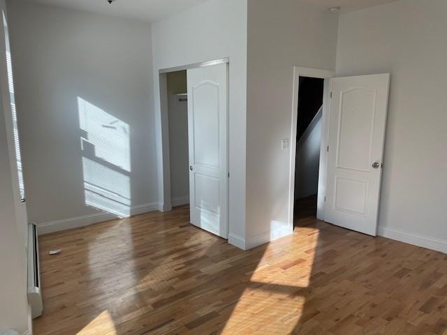 unfurnished bedroom with wood finished floors, baseboards, and a closet